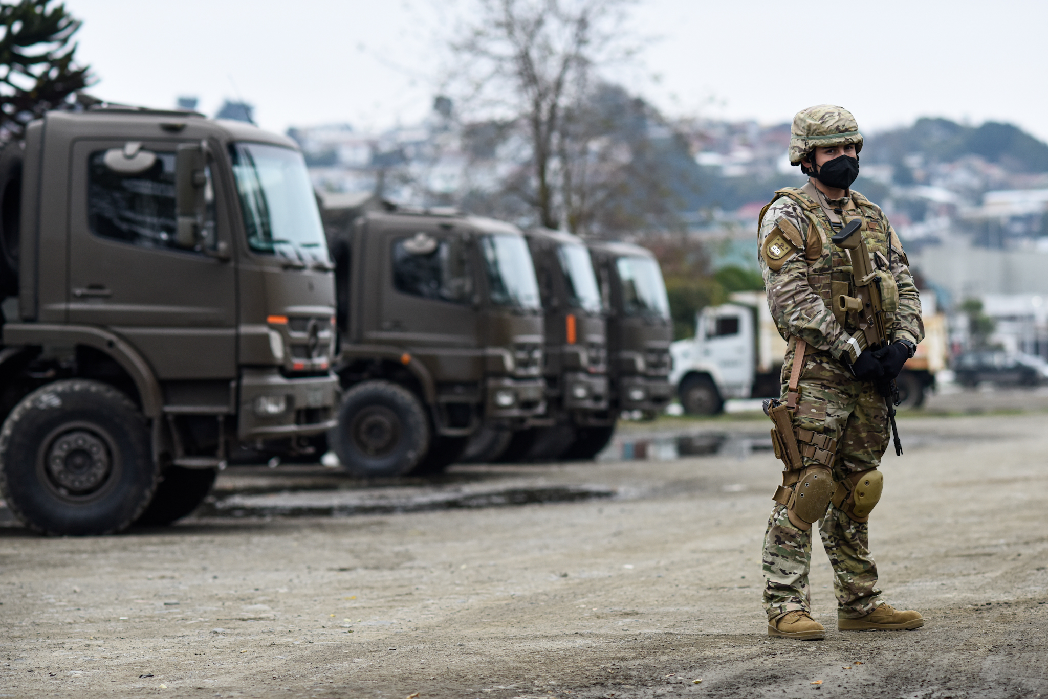Militar de pie frente a camiones militares. Estado de sitio.