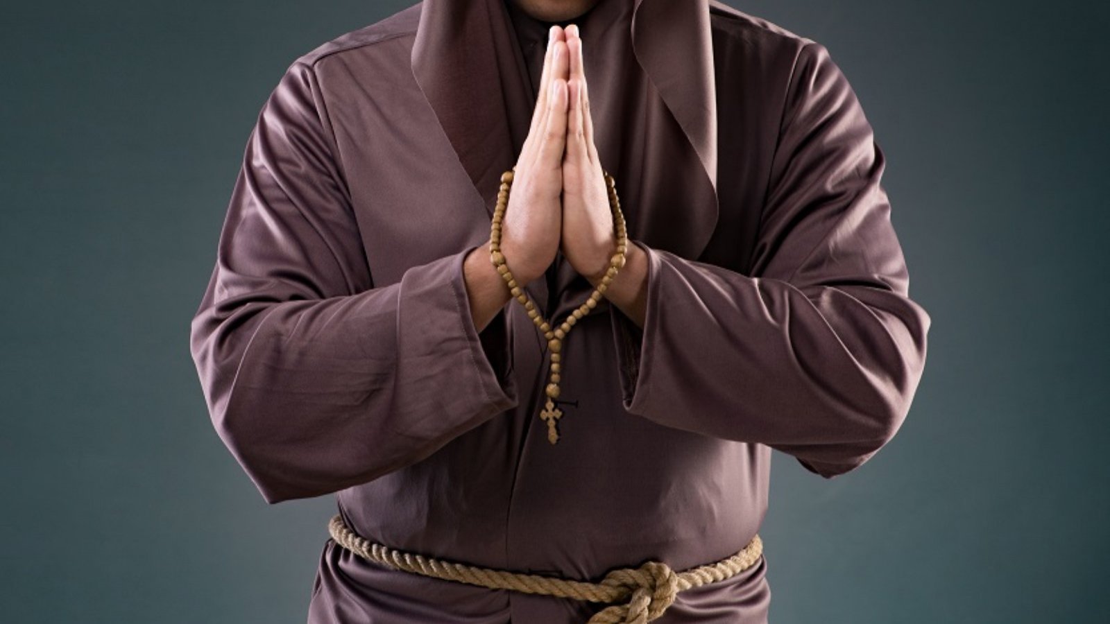 Persona en túnica de monje con las manos en posición de rezo.