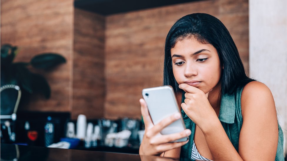 Una joven mira su teléfono con preocupación