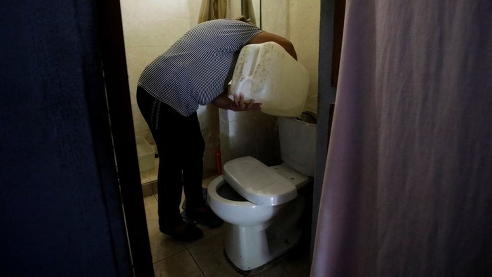 Un hombre vierte agua en un tanque de baño