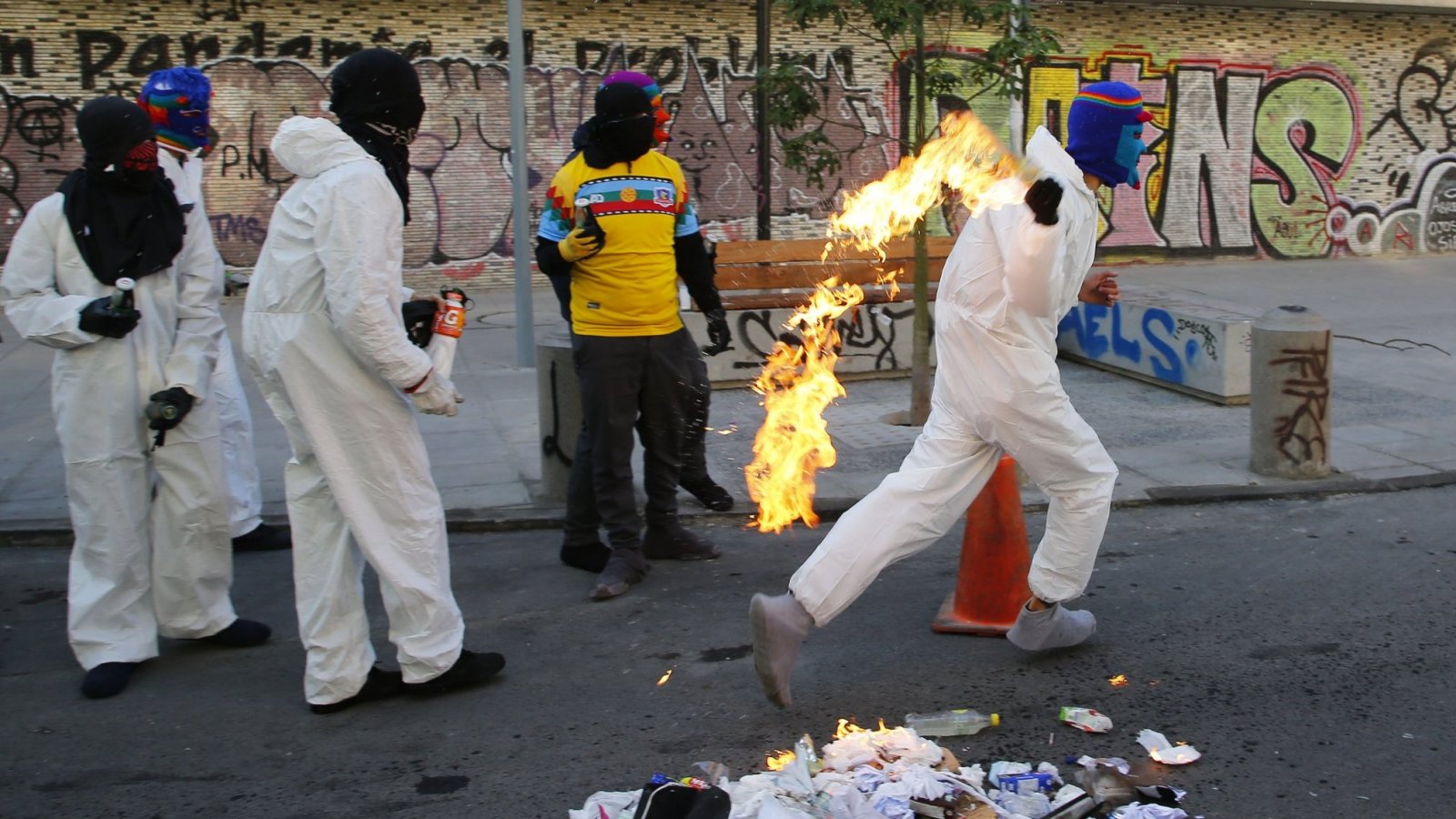 Persona con polerón del Instituto Nacional lanzando una bomba Molotov frente al emblemático establecimiento.