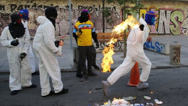 Persona con polerón del Instituto Nacional lanzando una bomba Molotov frente al emblemático establecimiento.