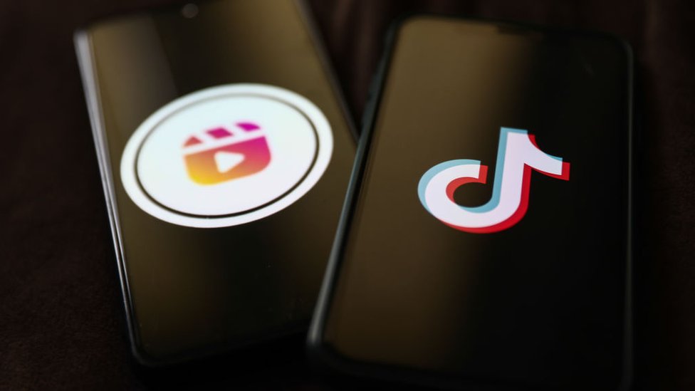Smartphone displaying Instagram Reels logo beside another smartphone showing TikTok's logo