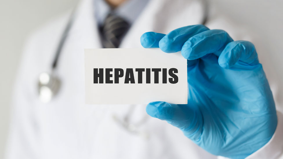 Un médico con una tarjeta que dice "hepatitis"