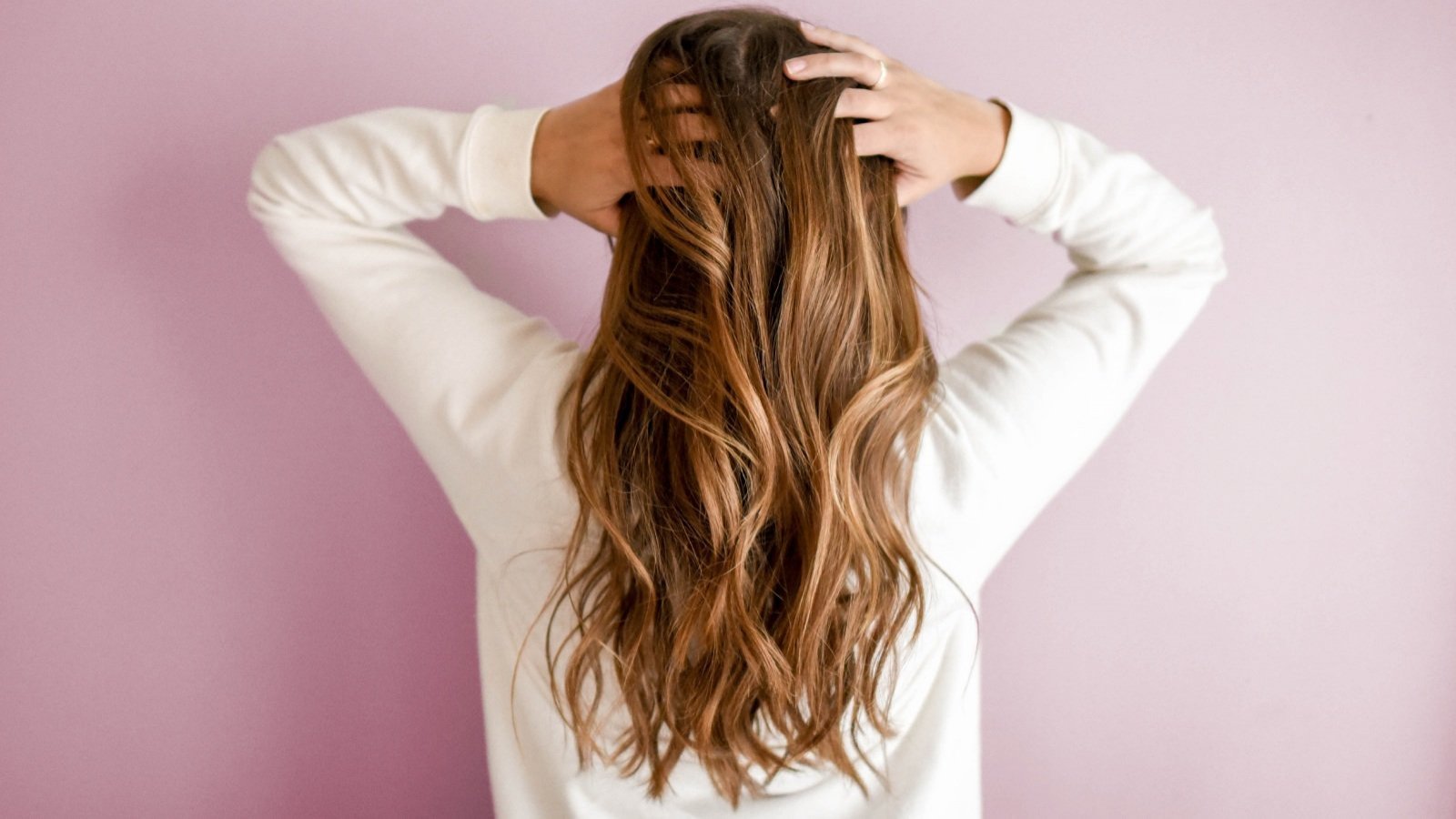 Mujer de espaldas tomándose el pelo