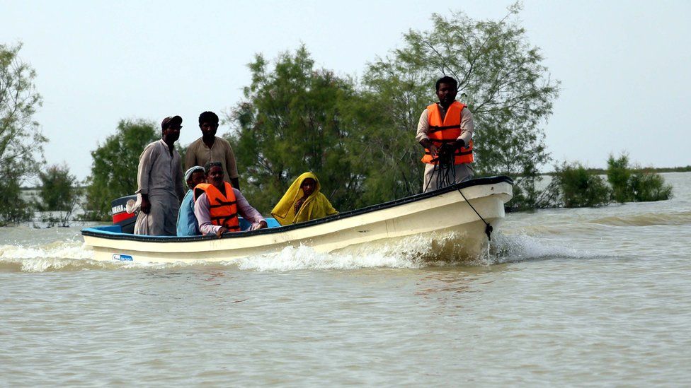 Personas huyendo en un bote de una inundación en Pakistán