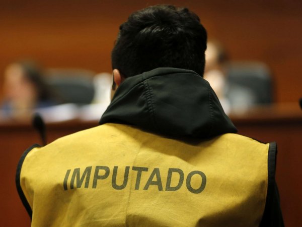 Imagen referencial de la espalda de un hombre en un tribunal, vistiendo una chaqueta amarilla que dice 
