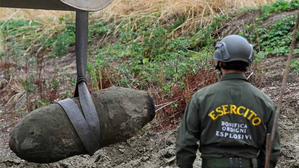 Un soldado mira una bomba que es removida de un río