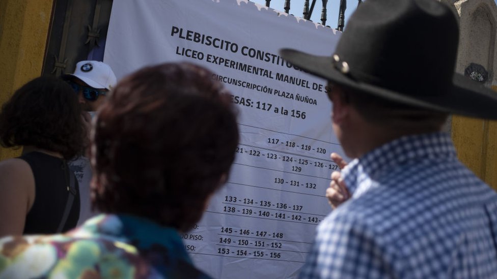 Dos personas buscan su nombre en las listas para votar.