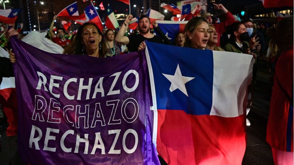 Manifestantes en las calles de Santiago de Chile con una bandera de rechazo.