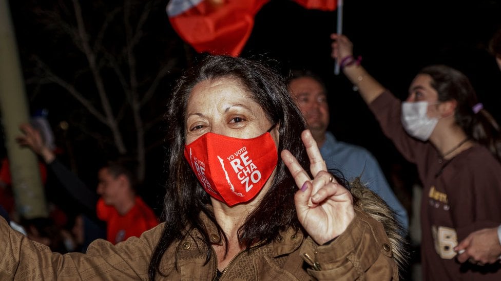 Una mujer con una mascarilla que dice "rechazo"