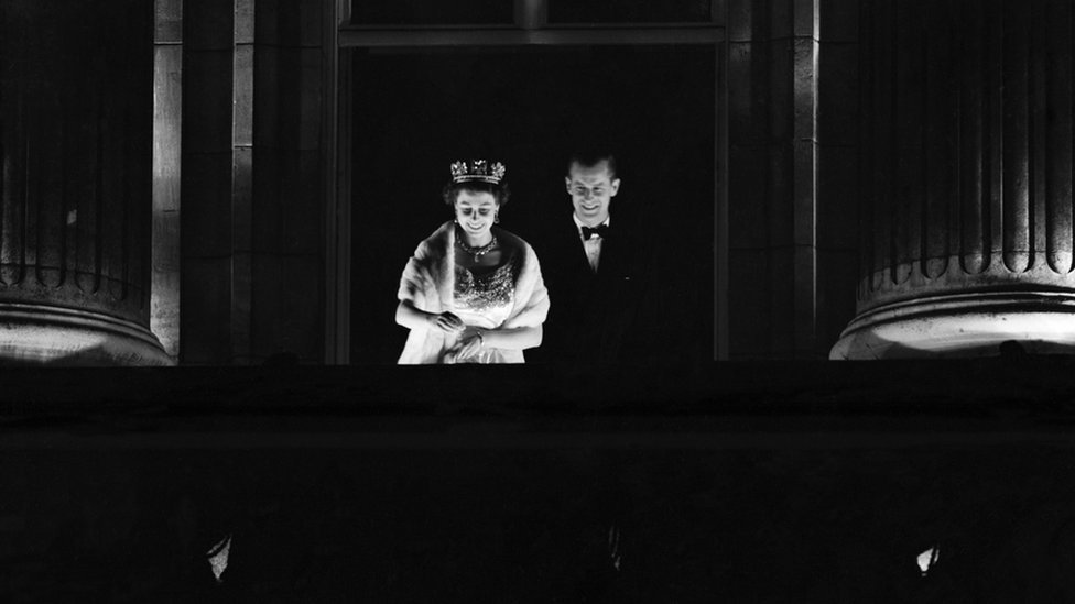 La reina Isabel II y el duque de Edimburgo hacen su aparición en el balcón del Palacio de Buckingham y saludan a la multitud que vitorea frente a las puertas.