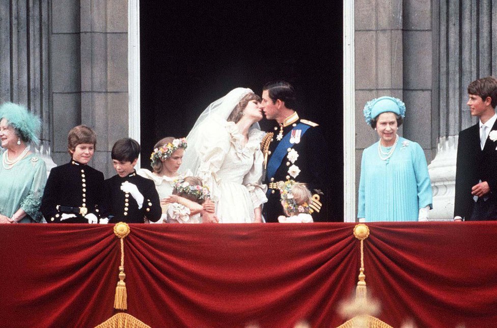 El príncipe Carlos y la princesa Diana se besan en el balcón del Palacio de Buckingham, el 29 de julio de 1981. Están rodeados por sus damas de honor y pajes, así como por la reina Isabel II, el príncipe Eduardo y la reina madre.
