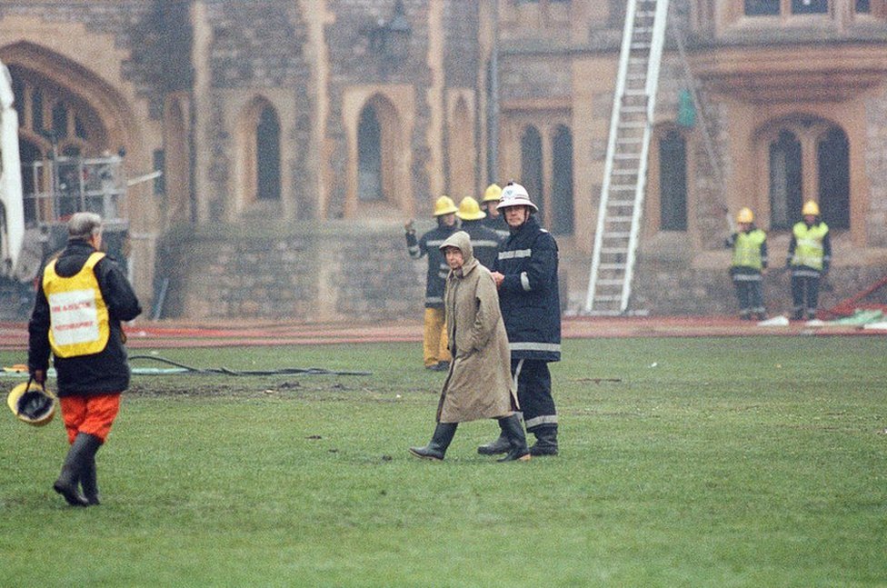 La reina es escoltada por el jefe de bomberos por los terrenos del Castillo de Windsor mientras los bomberos combaten un incendio, el 20 de noviembre de 1992.