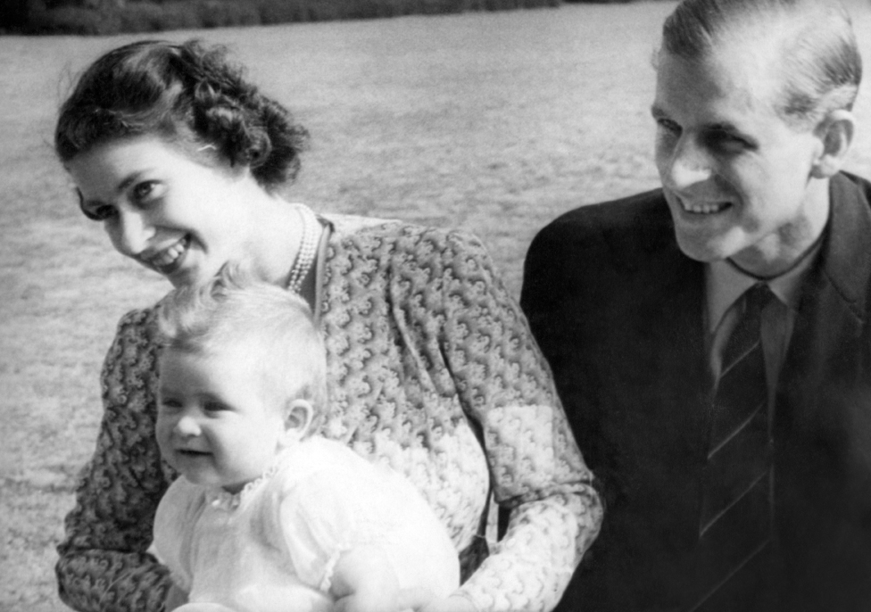 La princesa Isabel de Inglaterra y su esposo, el príncipe Felipe, duque de Edimburgo, con su bebé, el príncipe Carlos, en julio de 1949 en Windlesham Moor, Surrey.