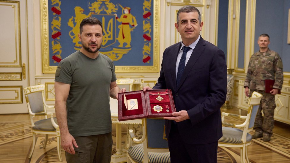 Presidente le da la medalla al mèrito.