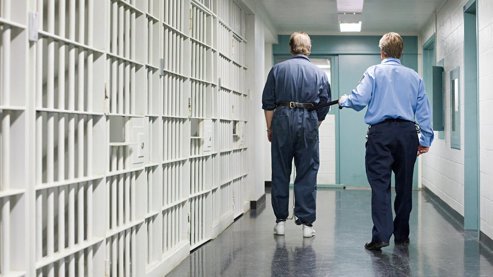 Un guardia conduce a un preso a su celda