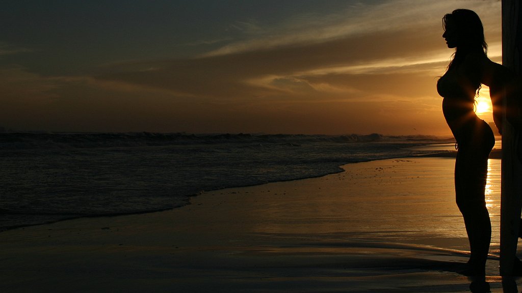 Silueta de chica en playa al atardecer con trasero salido