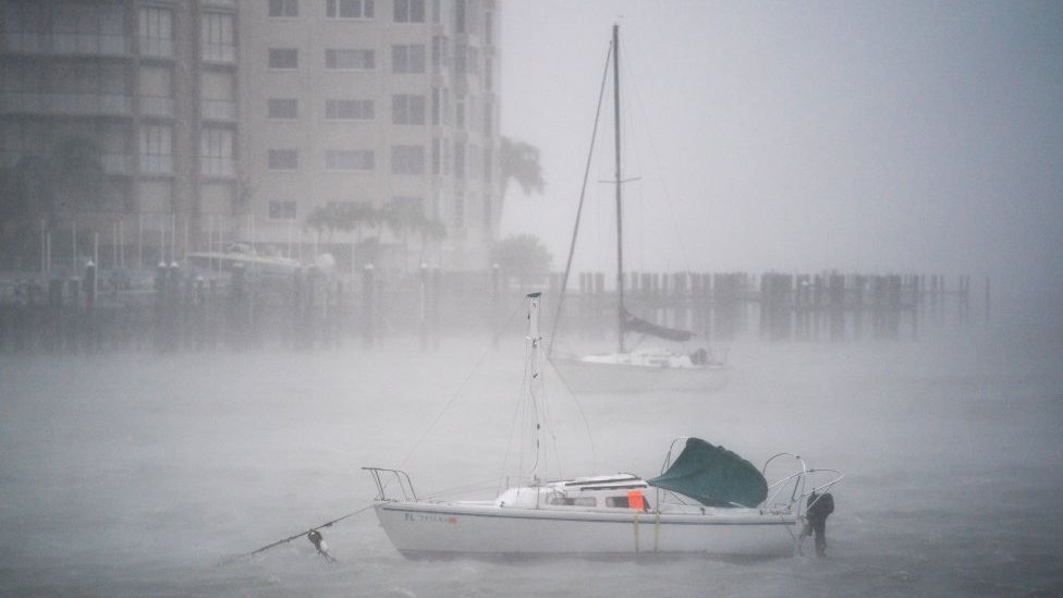 Barco en mitad de una marina, apenas se ve por la neblina causada por el fuerte viento y la lluvia.