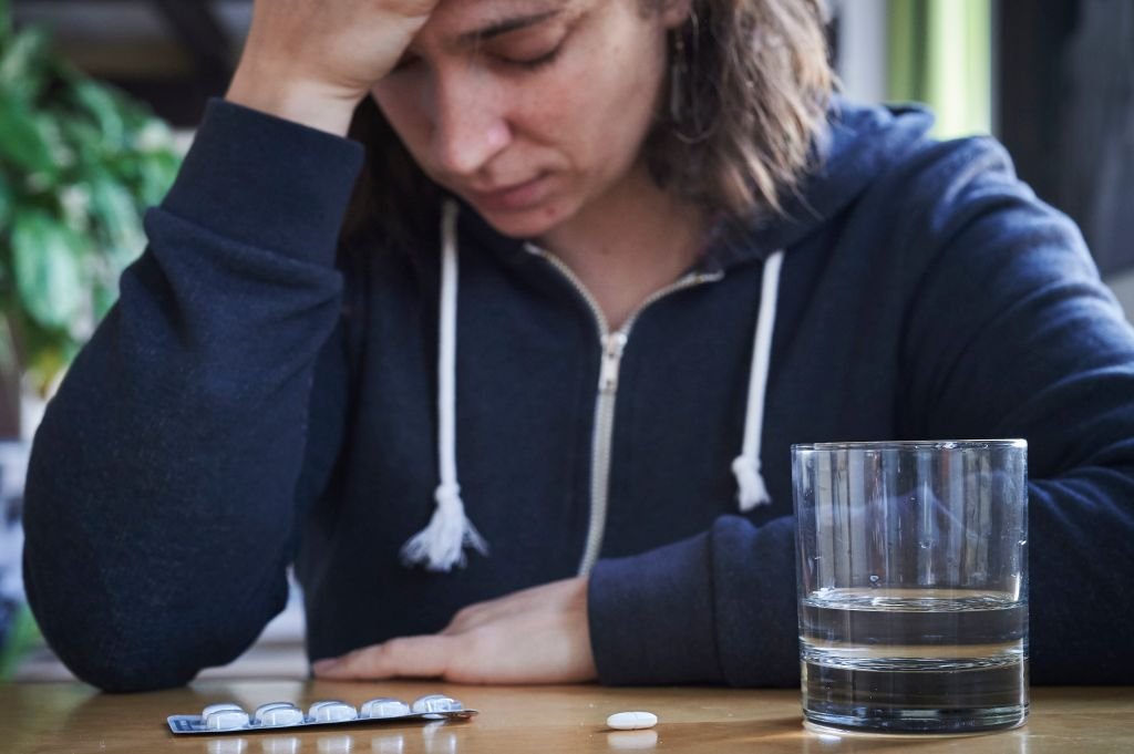 Mujer con pastillas y un vaso de agua.