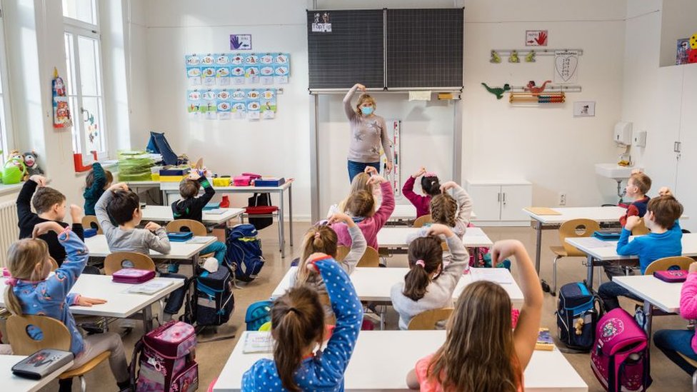 Una profesora da clases en un colegio a un grupo de niños