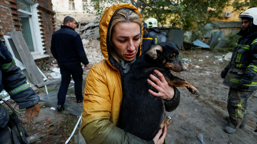 Una mujer local lleva a su perro en el sitio de un edificio residencial gravemente dañado por un ataque con misiles rusos, en medio del ataque de Rusia contra Ucrania, en Mykolaiv, Ucrania.