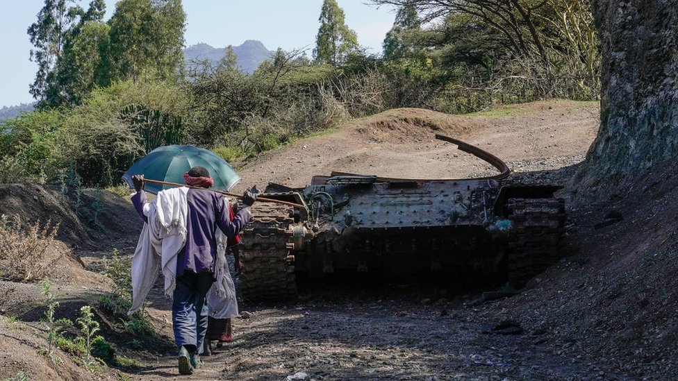 Un hombre pasando por los restos de un tanque.