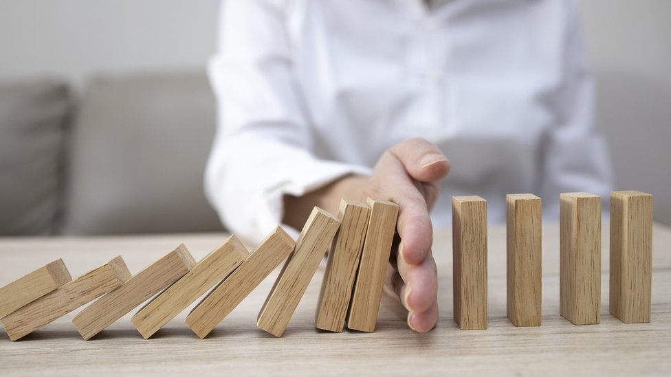 Una persona detiene una pila de maderas que se caen