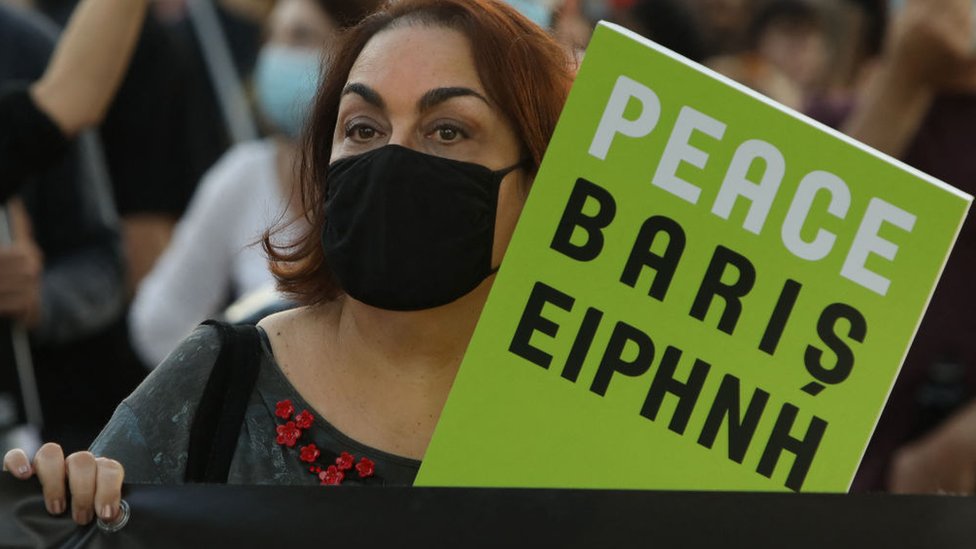 Una mujer sostiene una pancarta que dice paz en varios idiomas