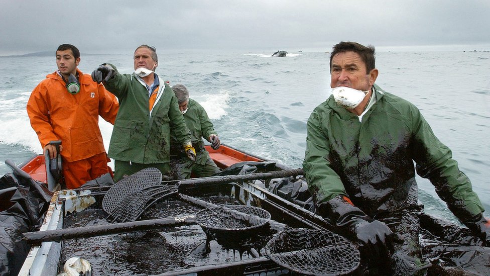Pescadores recogiendo fuel del mar en Galicia