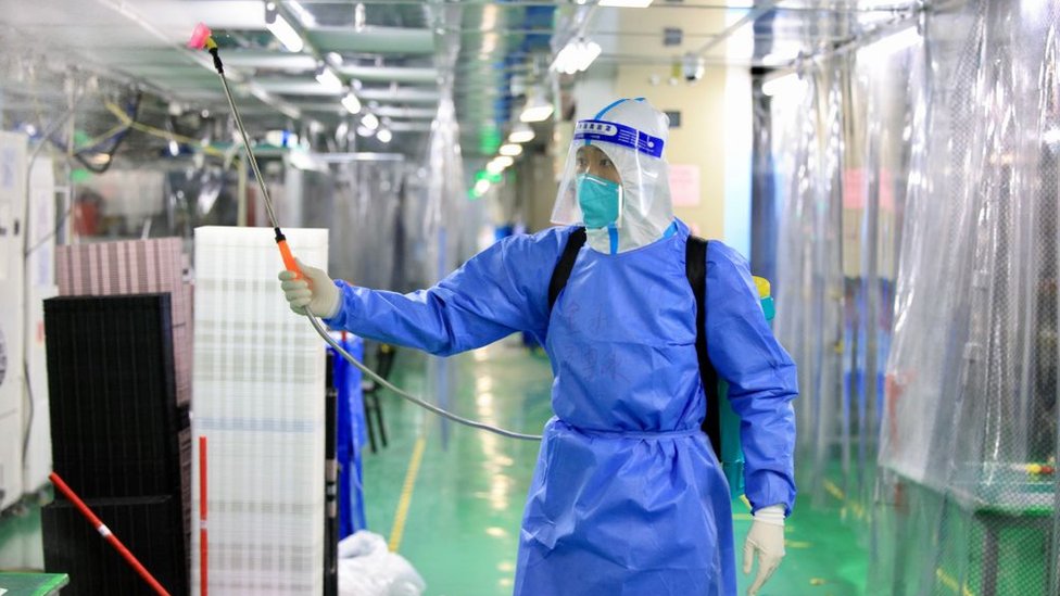 Un empleado de Foxconn en traje de protección personal desinfecta la planta en Zhengzhou
