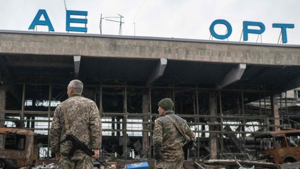 Soldados ucranianos al frente de un edificio en ruinas.