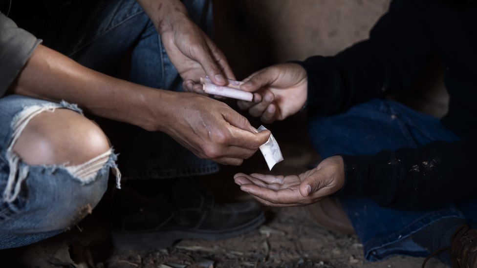 Un chico vendiéndole drogas a otro.