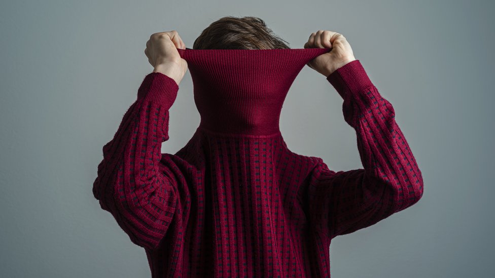 Un joven oculta su cara bajo su sweater.
