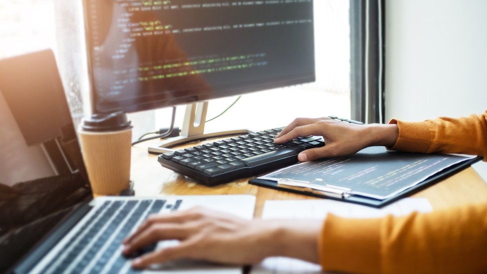 Un programador trabajando en dos computadores.