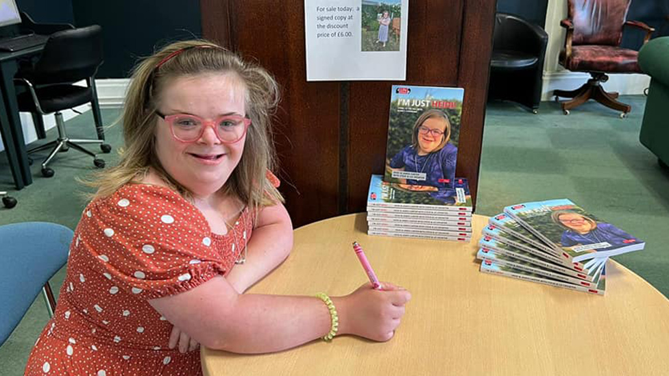 Heidi firmando copias de su libro