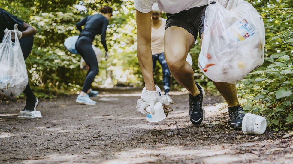 Corredores recogiendo basura en un camino por el bosque