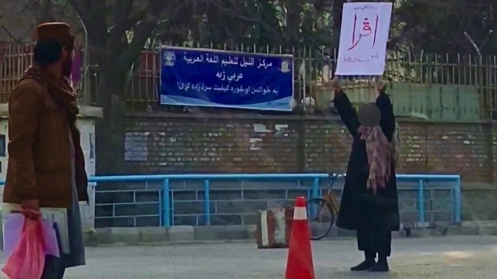 Adela sosteniendo la palabra del Corán frente a la universidad.
