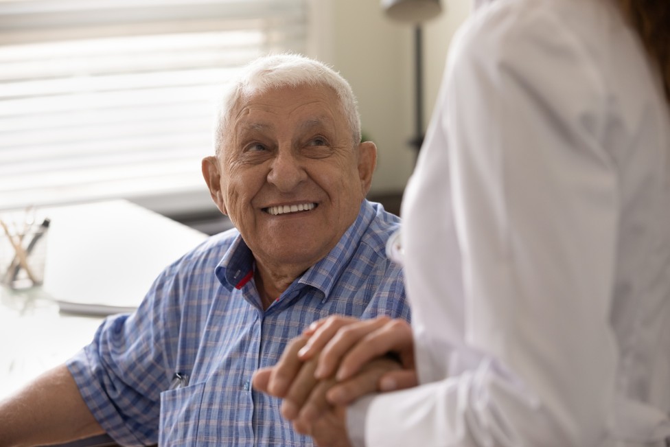 Un adulto mayor le sonríe a una doctora