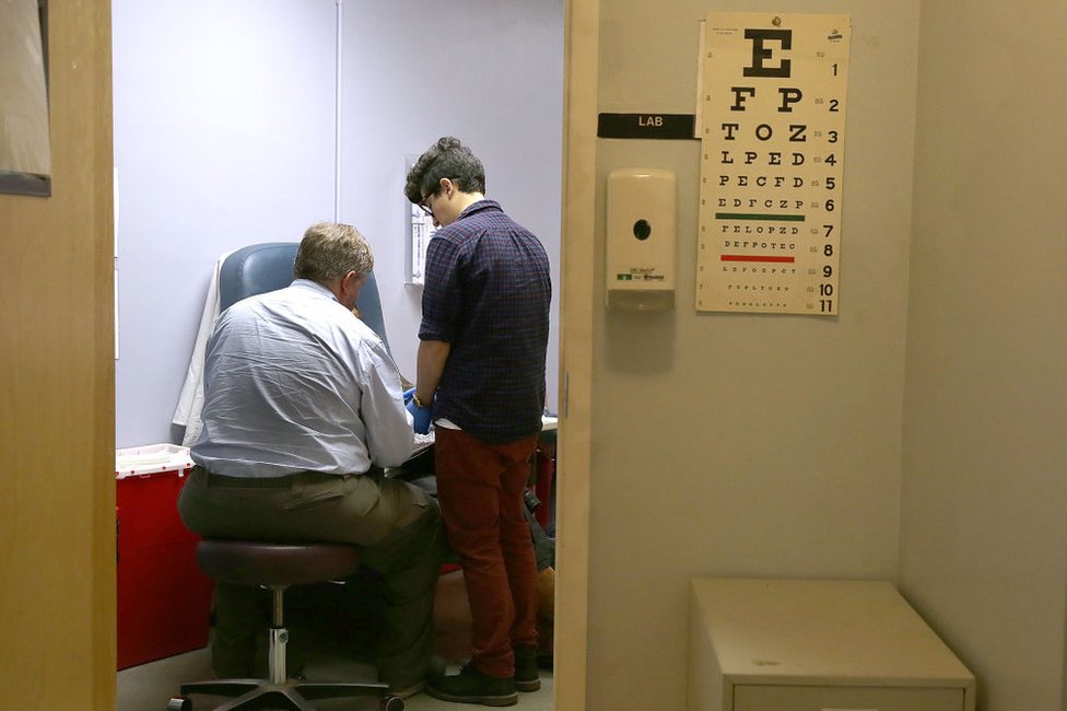 El doctor Nick Gorton (izquierda) con una paciente (sentada/no vista) en los Servicios de Salud de la Mujer de Lyon-mMartin, una clínica para mujeres trans en San Francisco, California, el 3 de noviembre de 2016.