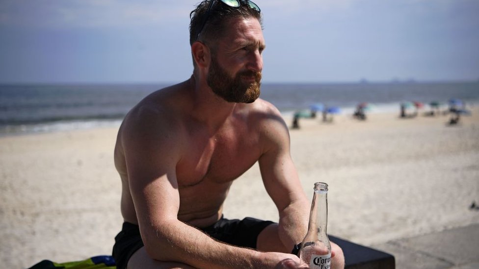 Un hombre bebe cerveza en la playa