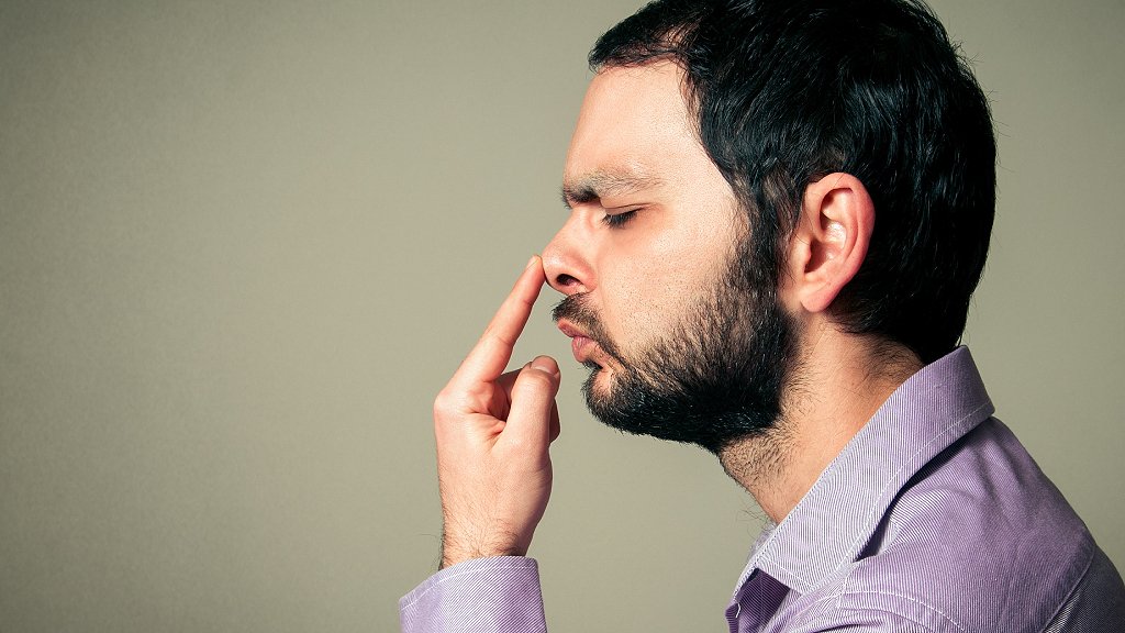 Hombre tocándose la nariz con los ojos cerrados