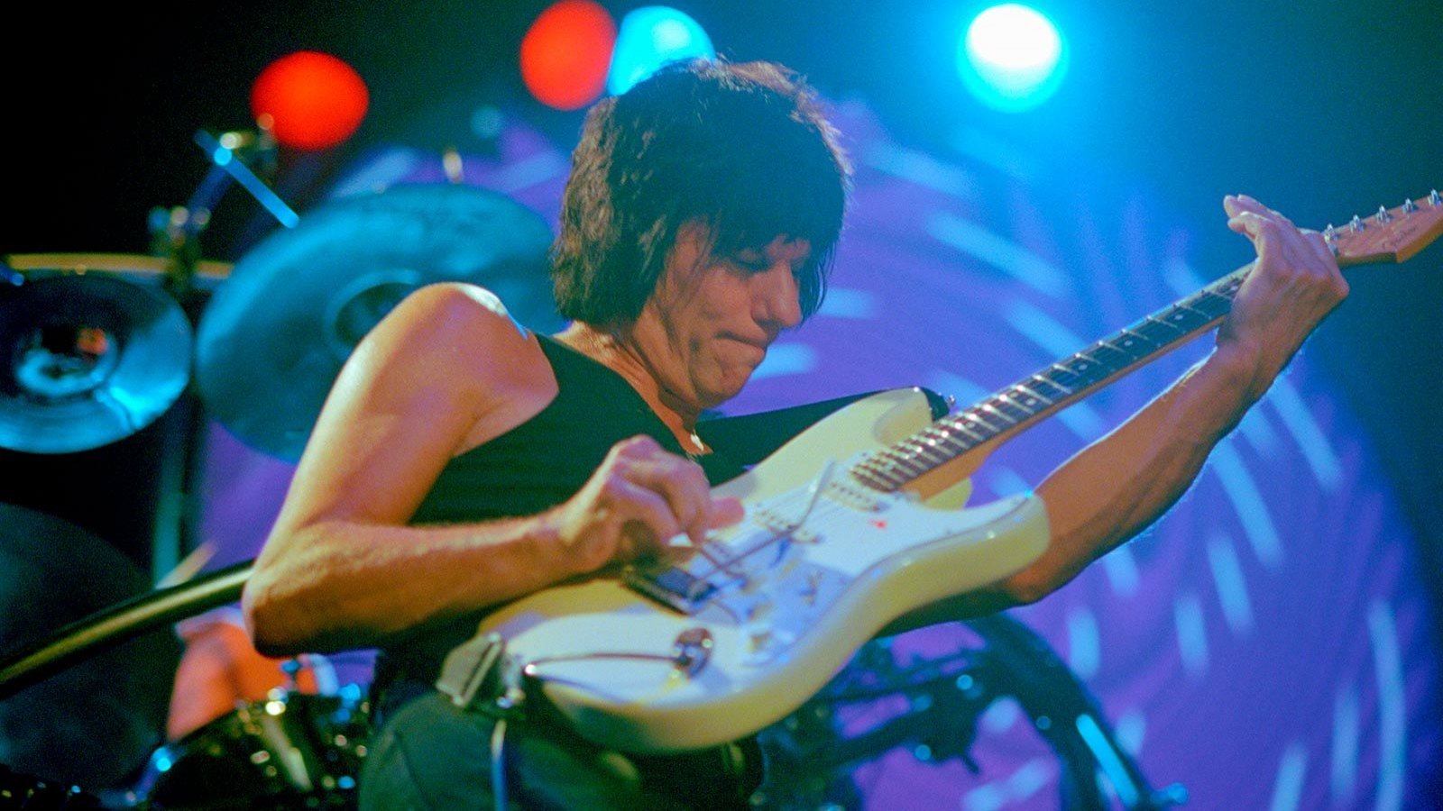 Jeff Beck tocando guitarra en un concierto en vivo.