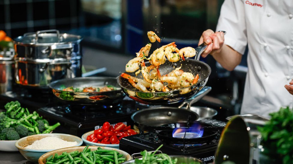 Un cocinero preparando un plato con mariscos.