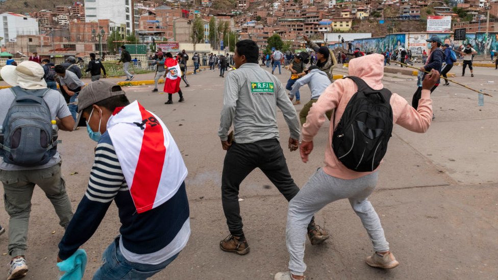 Manifestantes lanzando piedras contra la poli{ia en Cusco.