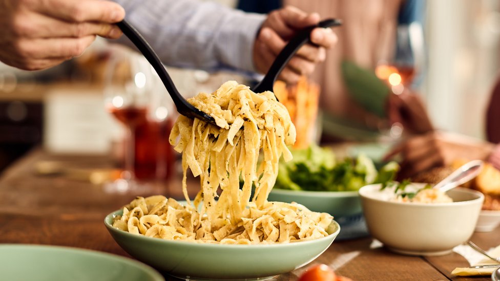 Un hombre sirviendo un pasta.