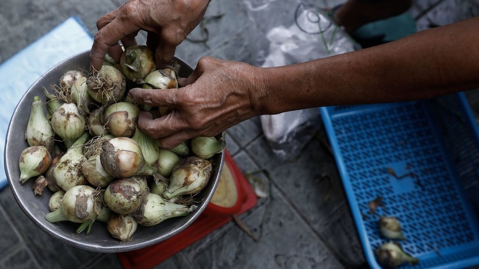 Una cazuela llena de cebollas en un mercado