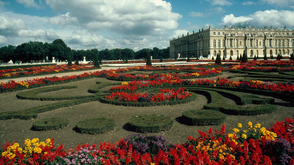 Palacio a la derecha, jardines en frente y bosque en el fondo