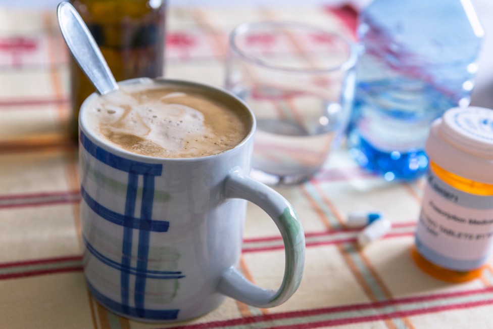 Taza de café al lado de un medicamento