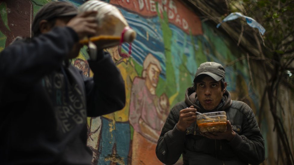 Dos argentinos se alimentan de la comida ofrecida en un comedor de beneficencia.